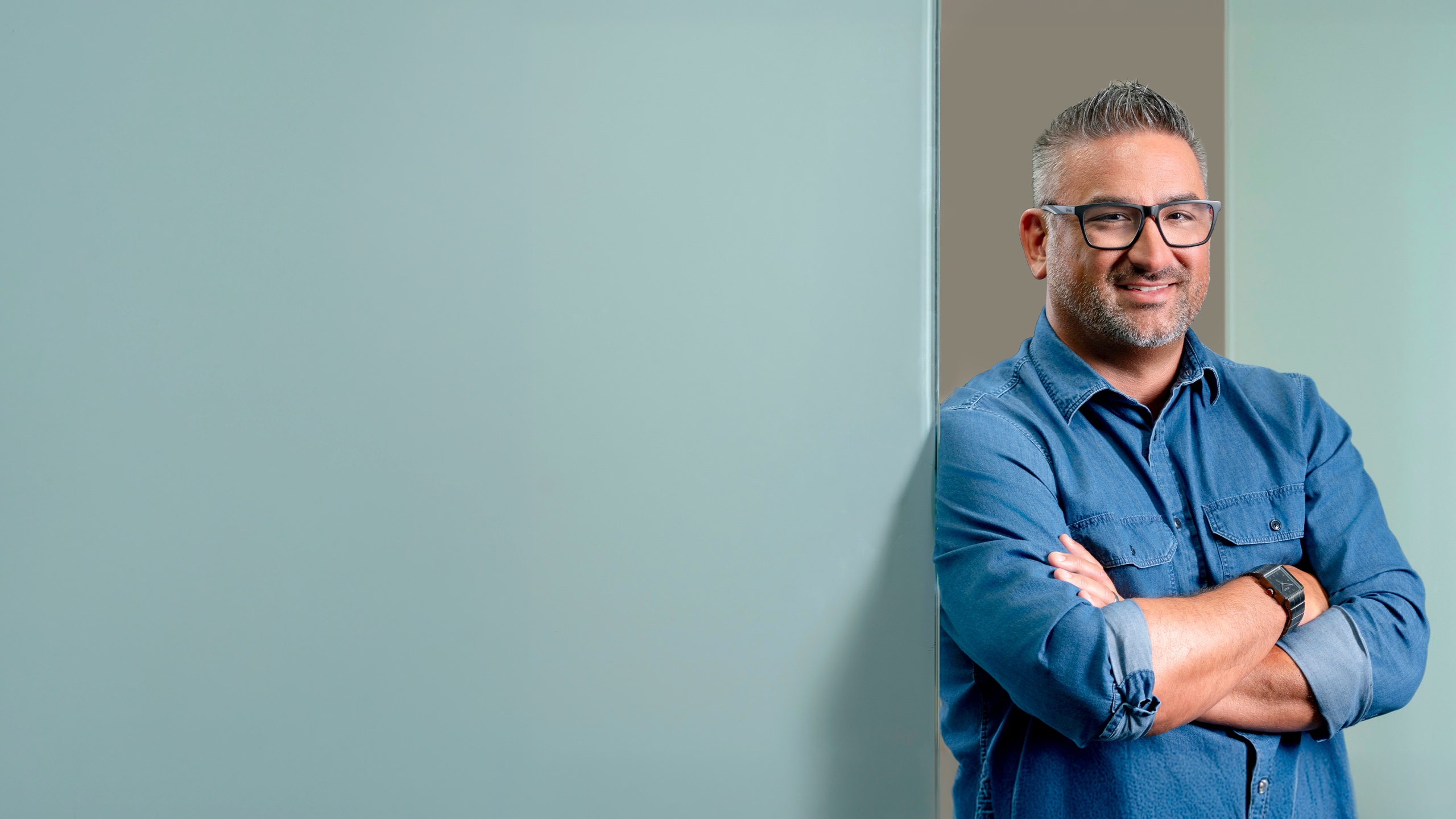 Smiling professional with glasses in a denim shirt